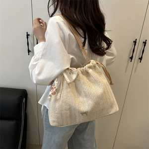 Handmade woven straw tote bag with floral lace trim and delicate metal bow pendant