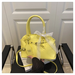Detail of yellow shell bag with white lace bow and detachable thin leather shoulder strap