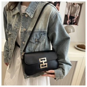 Minimalist black leather shoulder bag with a square gold buckle worn by a model