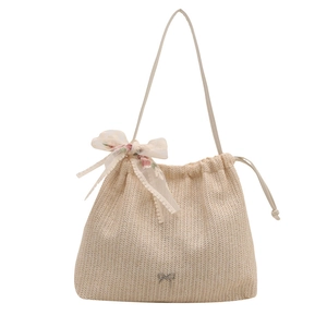Elegant beige woven bucket bag featuring floral lace bow and metallic butterfly logo
