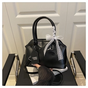 Close-up of black shell bag featuring white lace bow and branded leather tag