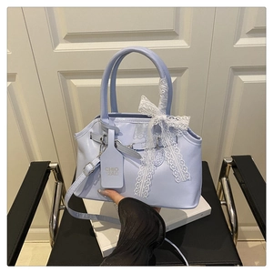 Macro detail of lavender crossbody bag featuring a delicate white lace bow on the handle