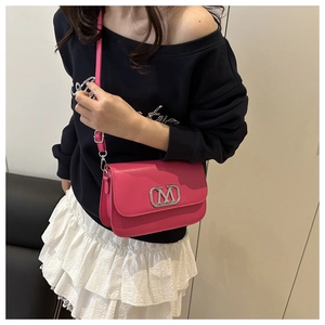 Gros plan sur un sac à bandoulière rose avec boucle en métal M argentée et cuir mat