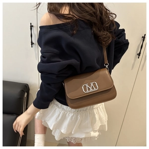 Sac bandoulière marron avec boucle logo M argenté porté par un mannequin
