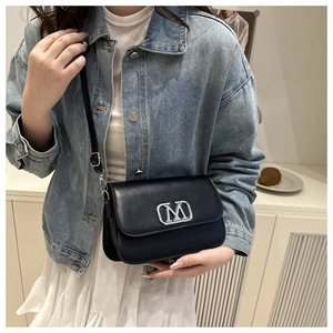 Détail d'un sac bandoulière noir en cuir PU avec boucle logo M argentée et sangle