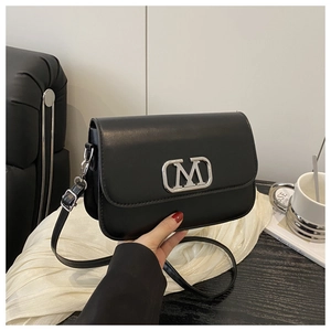 Détail du sac bandoulière en cuir noir avec logo M en métal argenté et bandoulière