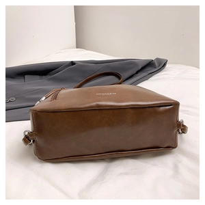 Close-up of brown vintage PU leather tote bag with silver hardware on white fabric