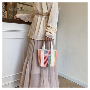 Close-up of vibrant multi-color woven tote bag with durable white fabric handles