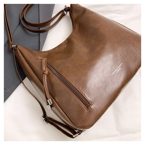 Macro shot of dark brown hobo bag showing metallic zipper pocket and brand debossing