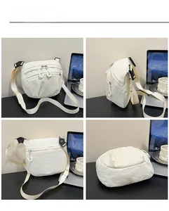 Detail showing white crossbody bag with multi-zipper compartments and wide nylon strap