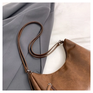 Detail of vintage brown crescent bag with silver zipper and textured leather finish