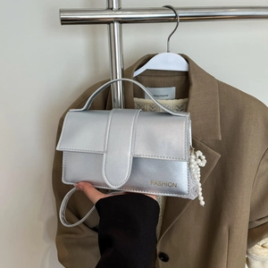 Close-up of a silver metallic crossbody bag with pearl tassel and fashion logo