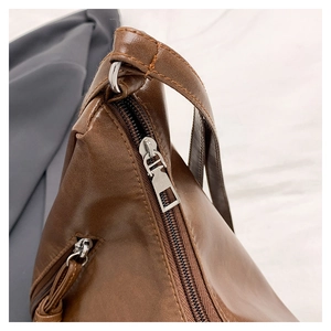 Detail of silver metal zipper and brown leather texture on a large tote bag