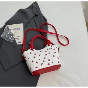 Detail of the vintage cherry print bucket bag showing red leather handles and strap