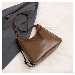 Flat lay of brown leather tote bag with adjustable strap and grey blazer lifestyle detail