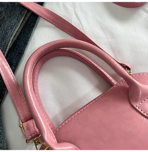 Detail of pink shell bag with leather texture, golden hardware and shoulder strap
