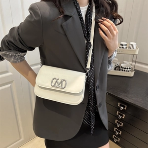 Sac bandoulière minimaliste en cuir blanc avec logo M argenté sur une veste