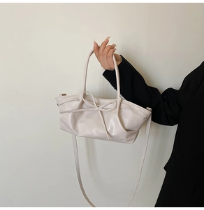 Détail d'un sac cabas beige avec nœud papillon, texture lisse et plis élégants