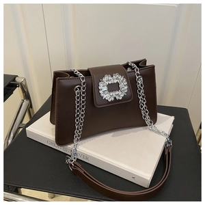 Close-up of the elegant dark brown leather handbag featuring a large crystal buckle