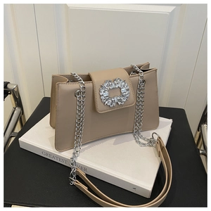 Detail of elegant beige crossbody bag featuring a sparkling rhinestone buckle and chain strap