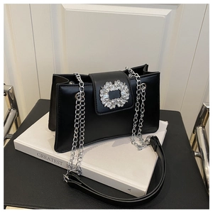 Macro detail of black leather crossbody bag featuring a sparkling crystal floral buckle