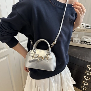 Silver metallic Boston crossbody bag with gold buckle detail shown on a model