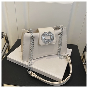 Detail of cream leather shoulder bag featuring a sparkling rhinestone buckle and silver chain
