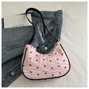 Dettaglio borsa rosa arricciata con piccoli fiocchi neri su giacca in denim e libro