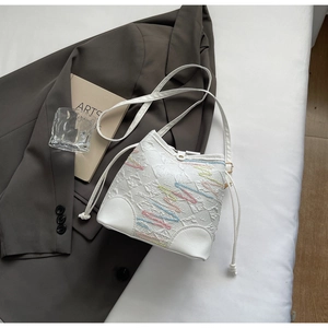 Detail of white bucket bag featuring colorful wave embroidery and drawstring closure