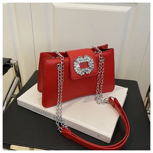 Detailed view of a red flap bag featuring a luxury rhinestone buckle and silver chain strap