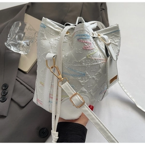 Detailed close-up of white bucket bag with colorful wavy embroidery and golden hooks