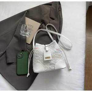 Detail of white bucket bag featuring colorful embroidered patterns and slim leather strap