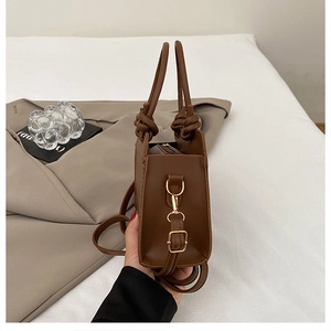 Detail of caramel brown tote bag with knotted handles and adjustable shoulder strap