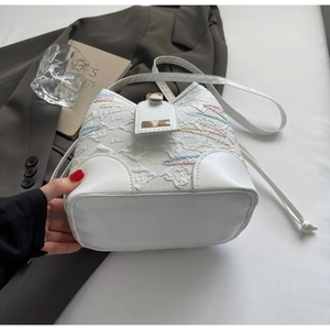 Detail view showing the oval base and colorful embroidery of the white bucket bag