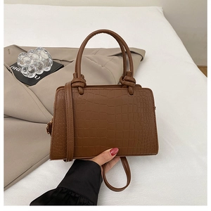 Detailed macro view of the brown crocodile texture and knot handle on a stylish tote bag