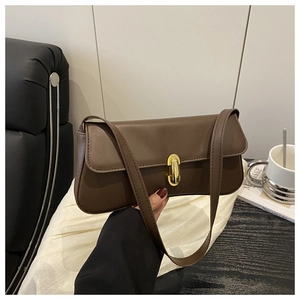 Close-up of a vintage brown leather baguette bag with a stylish gold oval metal clasp