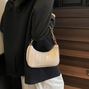 Woven straw hobo bag with gold chain strap worn over the shoulder by a model