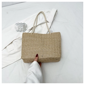 Detailed close-up of a beige woven tote bag with V-shaped texture on a white blazer