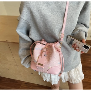 Detail of pink bucket bag featuring embossed patterns and slim crossbody leather strap