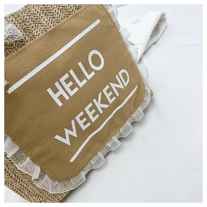 Detail of woven straw tote bag with Hello Weekend logo and delicate lace trim accents