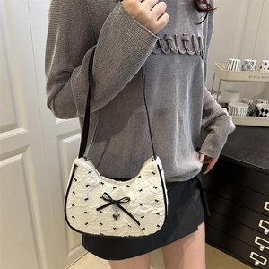 Borsa hobo bianca con fiocchi neri e ciondolo a cuore indossata da modella chic