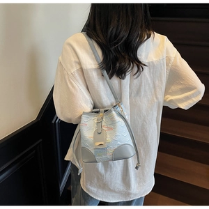 Detail of light blue bucket bag with wavy embroidery and textured pleats on a model