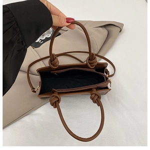 Detail of dark brown faux leather tote bag showing top handle knot and interior lining