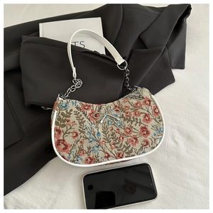 Close-up of floral tapestry underarm bag with silver bow detail and chain strap