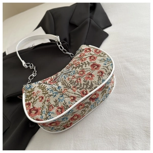 Detail of floral tapestry shoulder bag with silver bow charm and chain strap