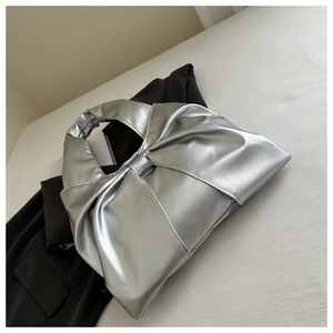 Macro detail of silver pleated tote bag with metallic finish and ruffled shoulder strap