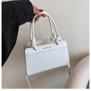 Detailed macro view of white crocodile pattern texture and gold text on handbag
