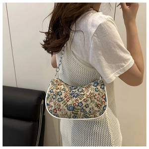 Detail of floral underarm baguette bag with silver bow accent and thick chain strap
