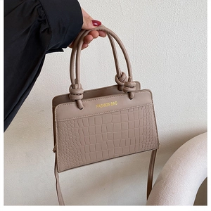 Detail of khaki faux leather tote with crocodile pattern and golden FASHION BAG text