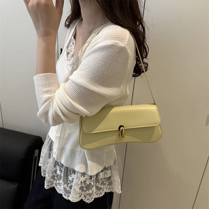 Minimalist light yellow shoulder bag with golden swivel lock and smooth leather finish
